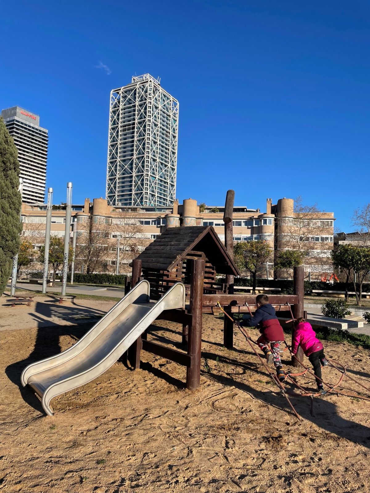 Nahuel y Alma Mía jugando en un parque de Barcelona, con el frente marítimo de la ciudad al fondo
